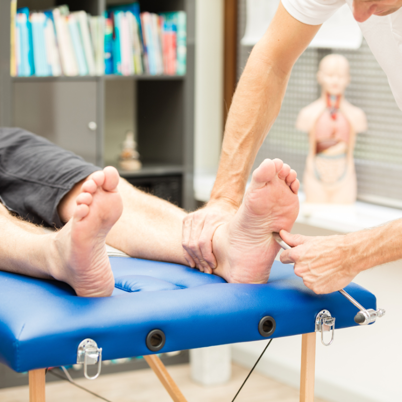 Person receiving treatment for neuropathy, therapist examining foot with a tool, clinical setting, focus on alleviating pain and discomfort associated with peripheral neuropathy.